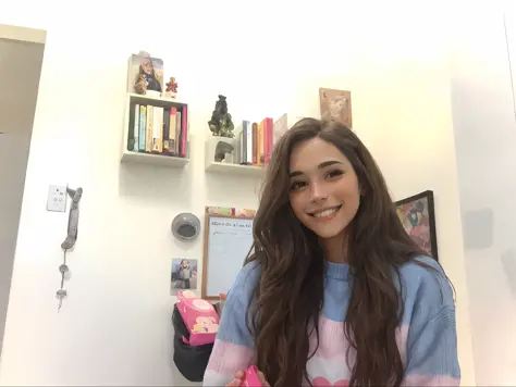 smiling woman in a blue and pink sweater holding a pizza, em seu quarto, Valentina Embaralhamento, happily smiling at the camera...