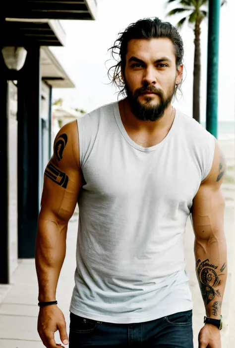 a man with a tattoo walking down a sidewalk on the sand at the beach, jason momoa, wearing a muscle tee shirt, wearing pants and a t-shirt, mid-shot of a hunky, he is a brown hairstyles ,tshirt, masculine and rugged, jason momoa as assyrian, colin farrell,...