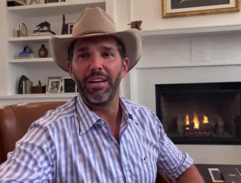 arafed man in a cowboy hat sitting in a chair in front of a fireplace