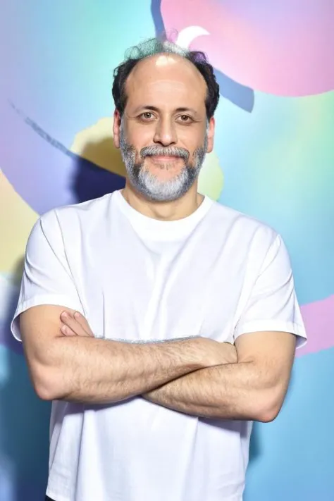 arafed man with a beard and a white shirt standing in front of a colorful wall