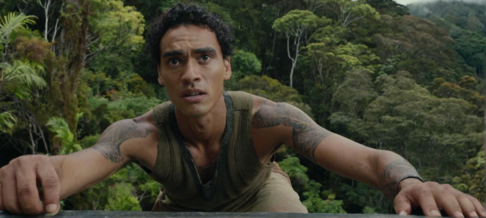 Un film encore un selfie d&#39;un grand, jeune, Homme maigre à moitié maori sur un rebord dans une forêt de Nouvelle-Zélande, avec un air légèrement inquiet sur son visage.



Cinématique, Photo du film