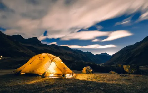 a tent is lit up at night in the mountains