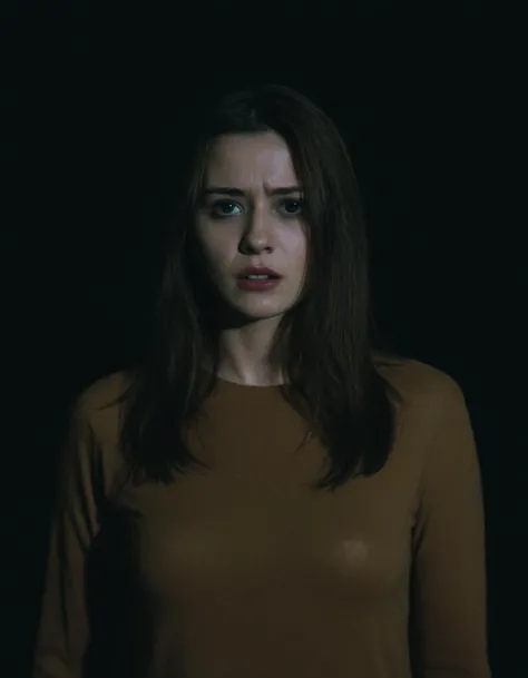 a woman in a brown shirt standing in the dark